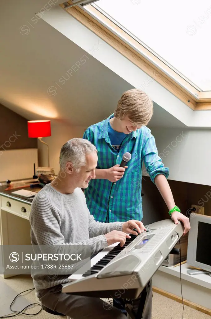 Man playing an electric piano with his son at home