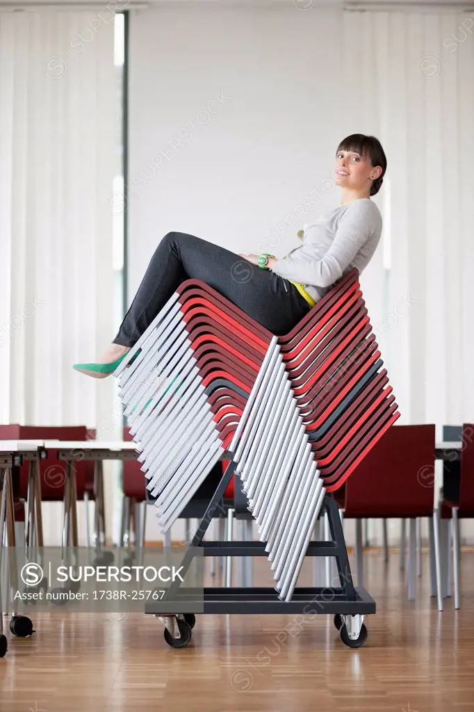 Businesswoman sitting on pileup chairs in an office