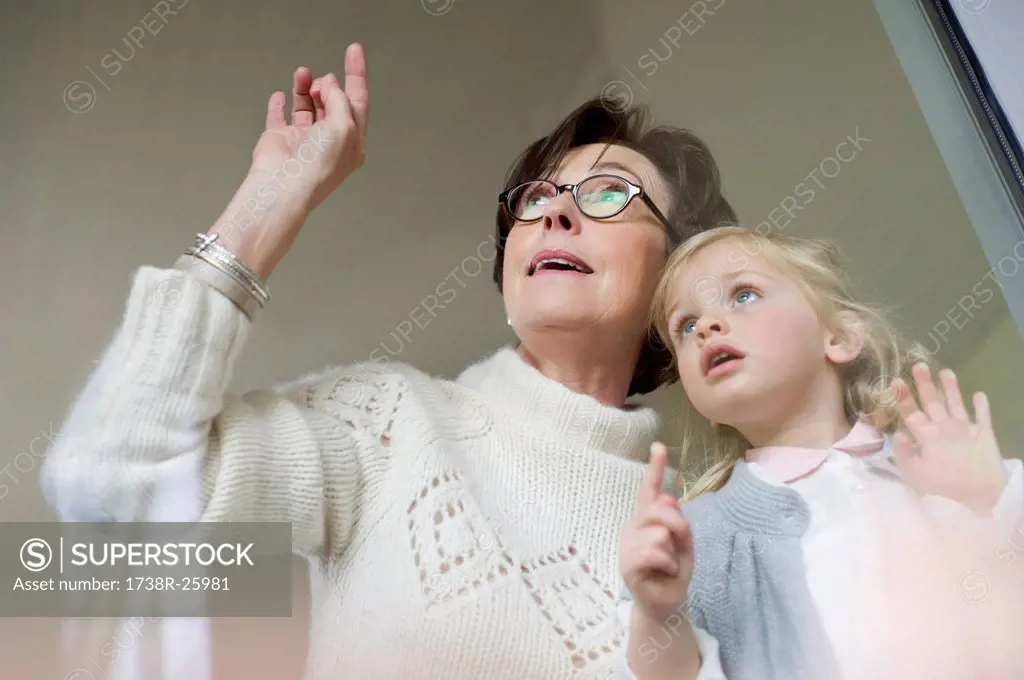 Woman with her granddaughter looking through a window