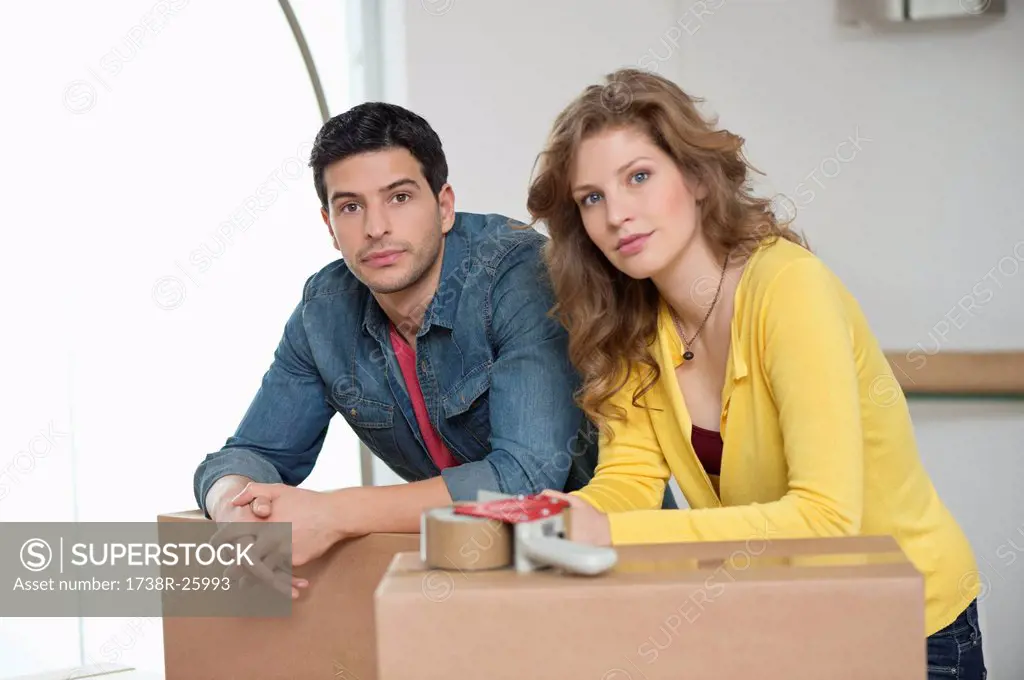 Couple leaning over cardboard boxes