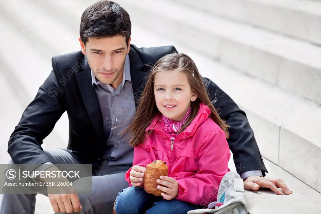Man sitting with his daughter eating pain au chocolat