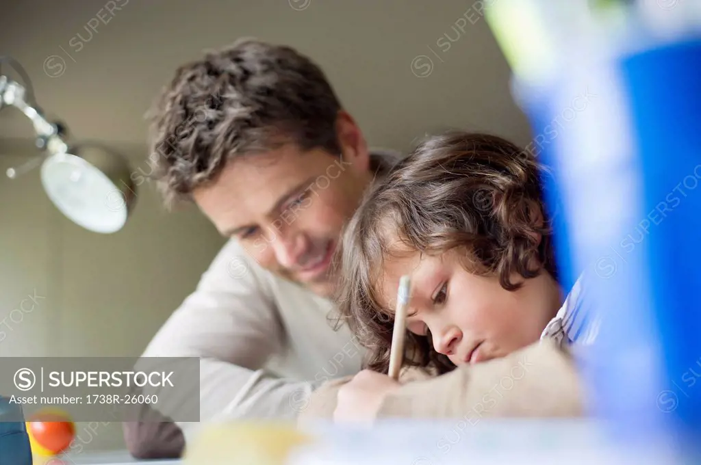 Boy studying with his father at home