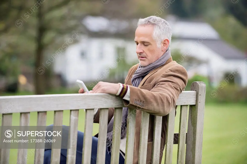 Man text messaging on a mobile phone in a park