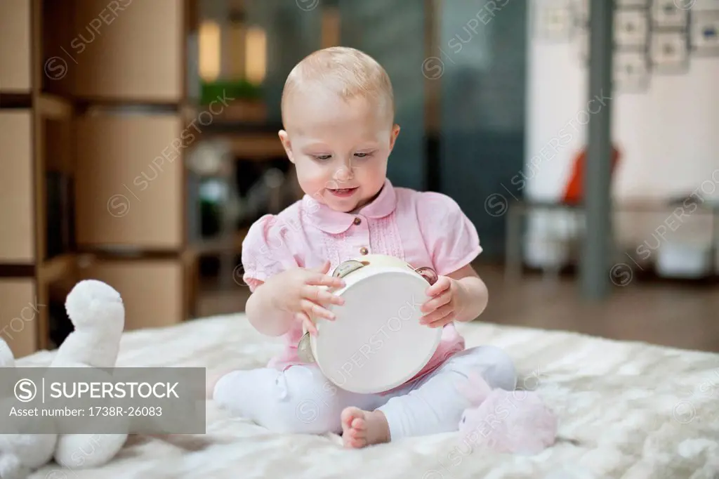 Baby girl playing with a tambourine