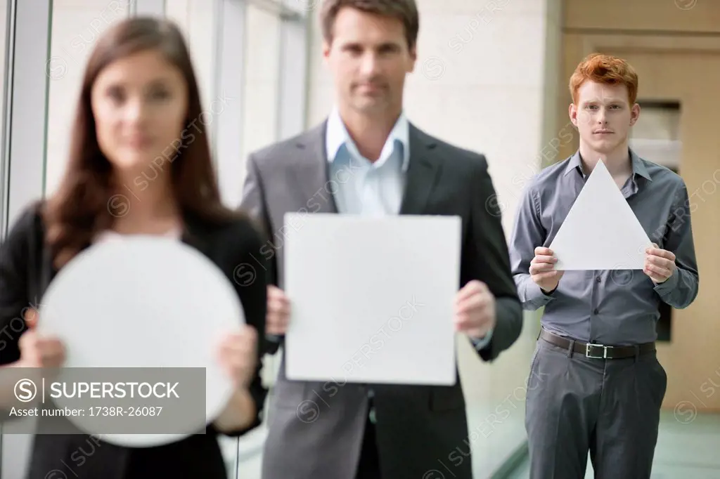 Business executives holding geometrical shaped placards in an office