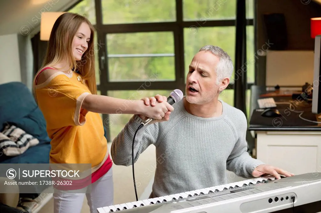 Man singing and playing a piano with his daughter at home