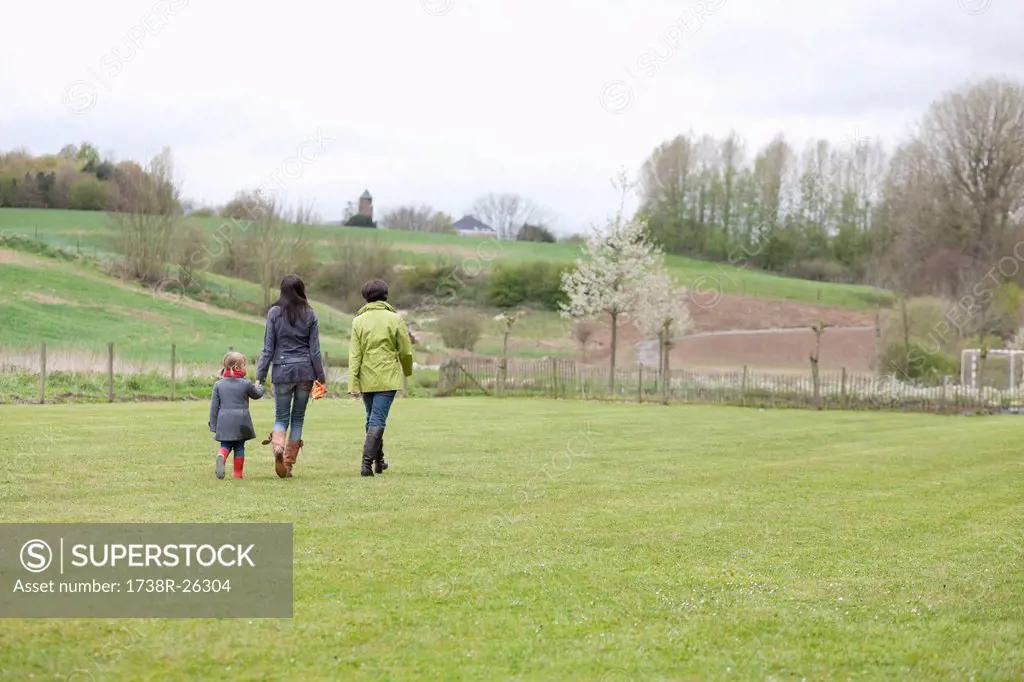 Girl walking with her mother and grandmother in a lawn