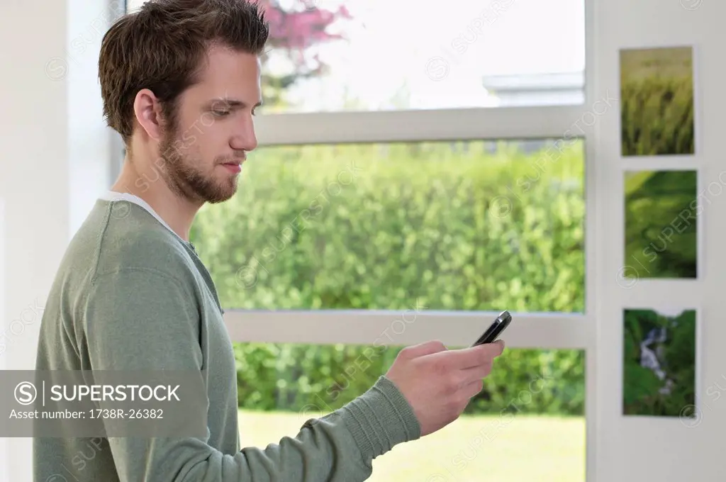 Man standing near a window using a mobile phone