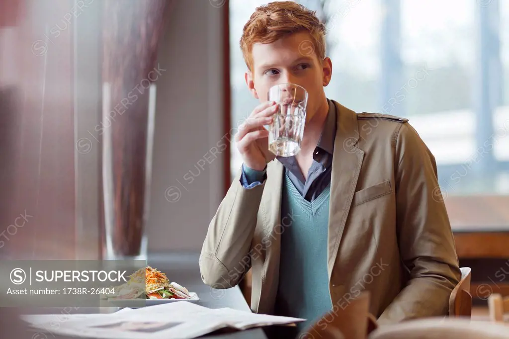Man sitting in a restaurant and drinking water