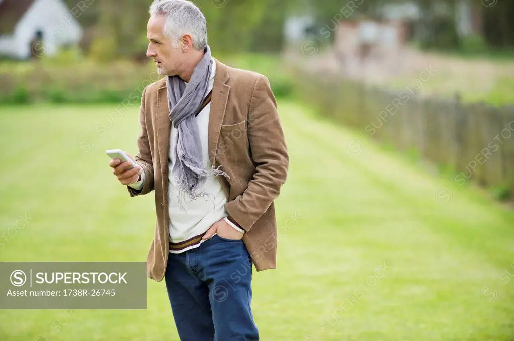 Man text messaging on a mobile phone in a lawn