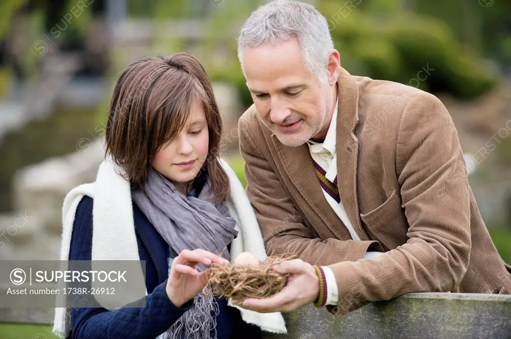 Man with his daughter holding a bird´s nest in a park