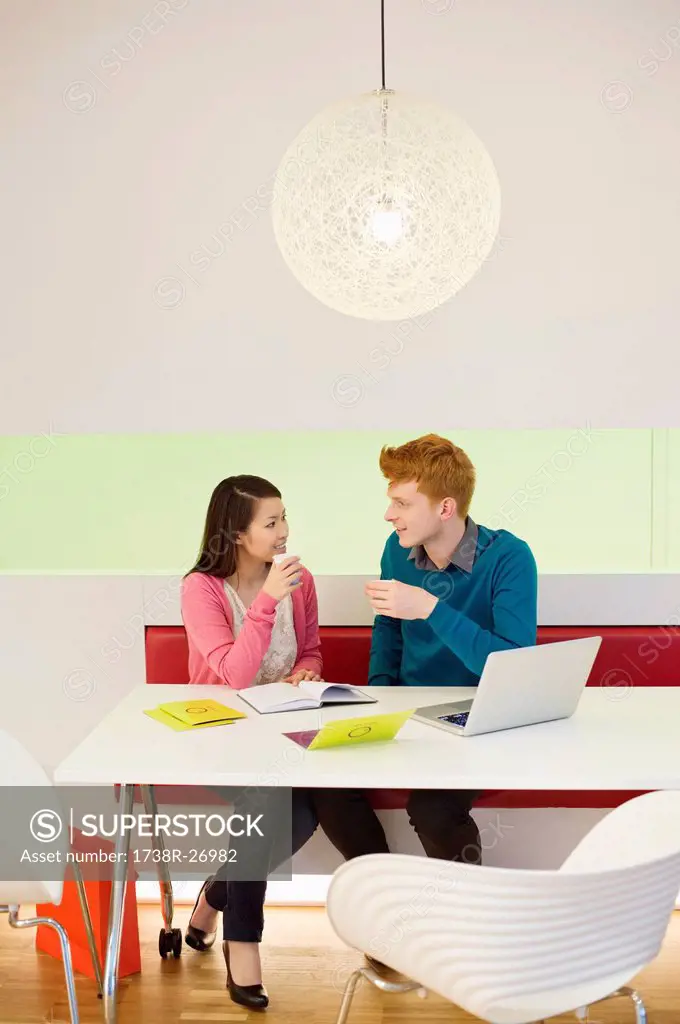 Business couple holding soft drinks and discussing in an office