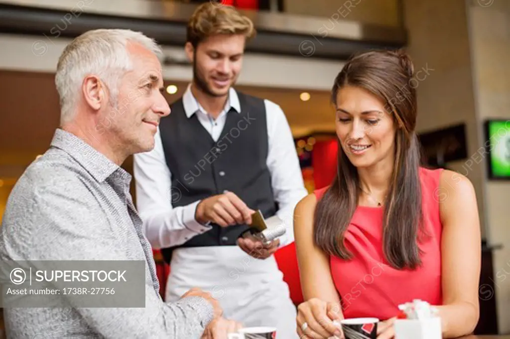 Couple paying with a credit card to a waiter in a restaurant