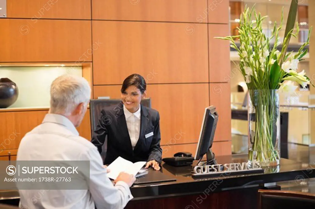 Businessman talking with a receptionist at the hotel reception counter