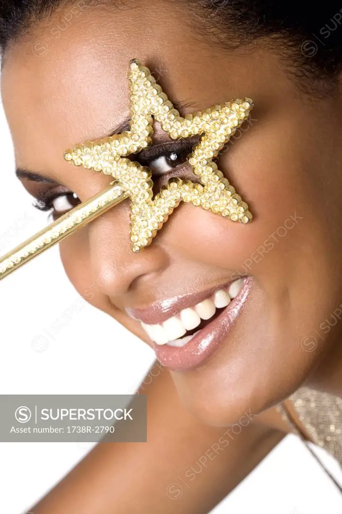 Portrait of a young smiling woman looking through magic wand