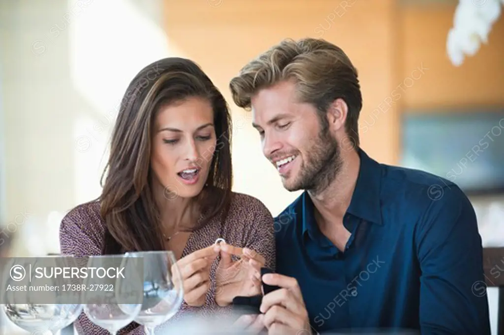 Man giving engagement ring to his girlfriend in a restaurant