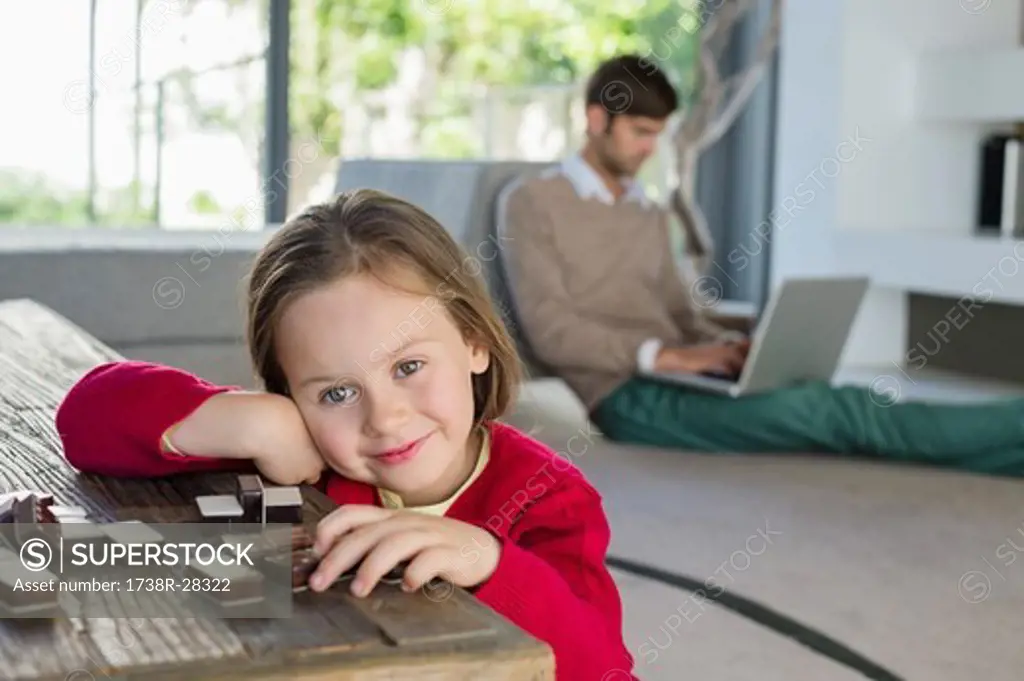 Portrait of a smiling girl with her father using a laptop in the background