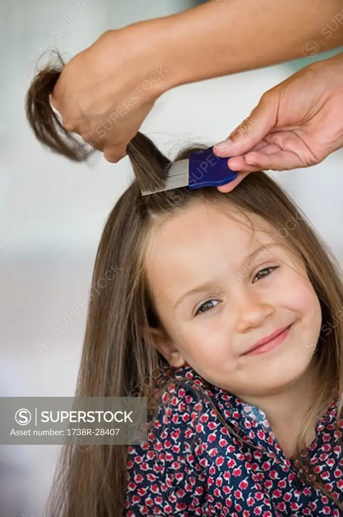 Close-up of a woman's hand combing her daughter's hair