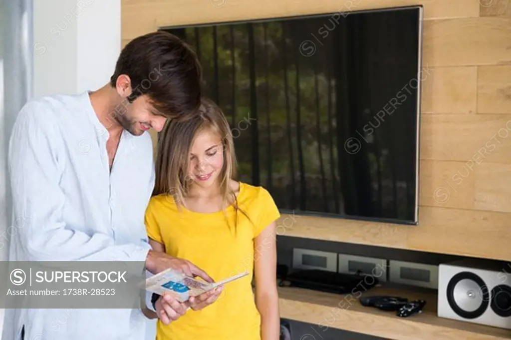 Man and his daughter looking at a CD