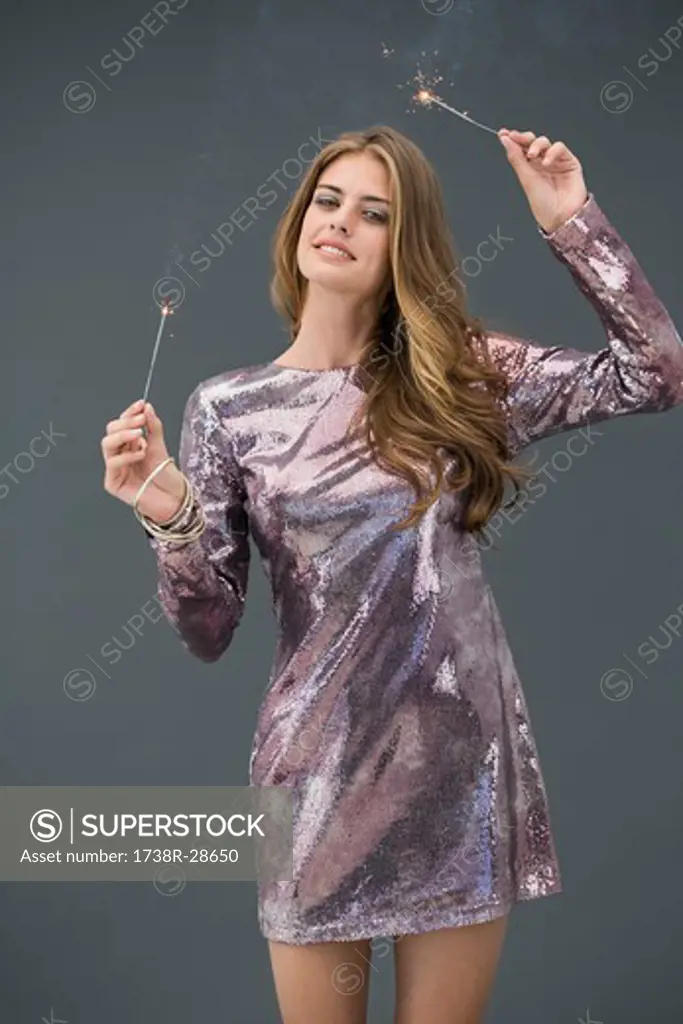Portrait of a woman celebrating with sparkler and smiling