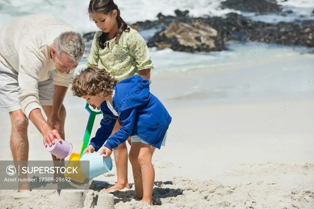 Children playing with their grandfather on the beach