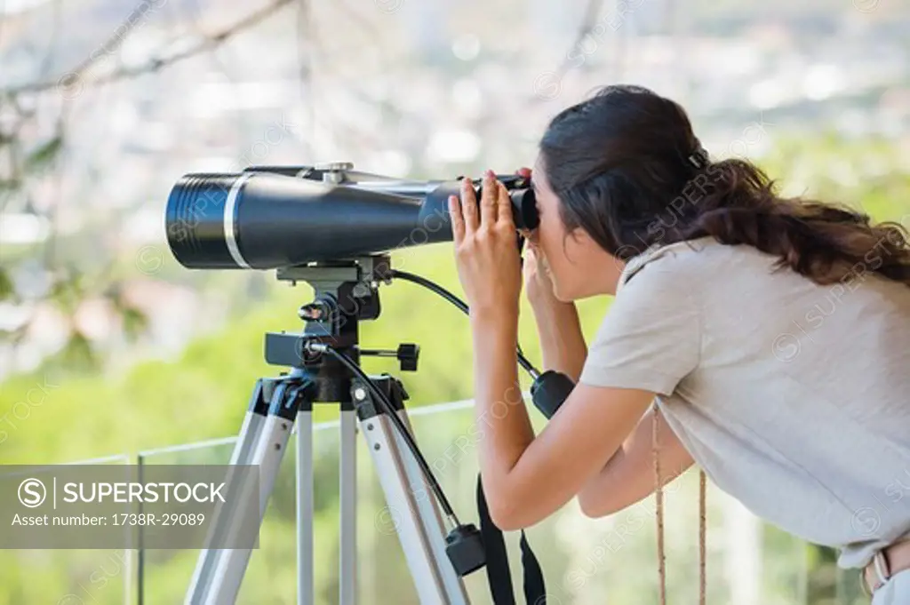 Woman looking through binoculars on tripod