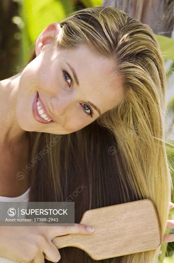 Portrait of a young woman brushing her hair, outdoors