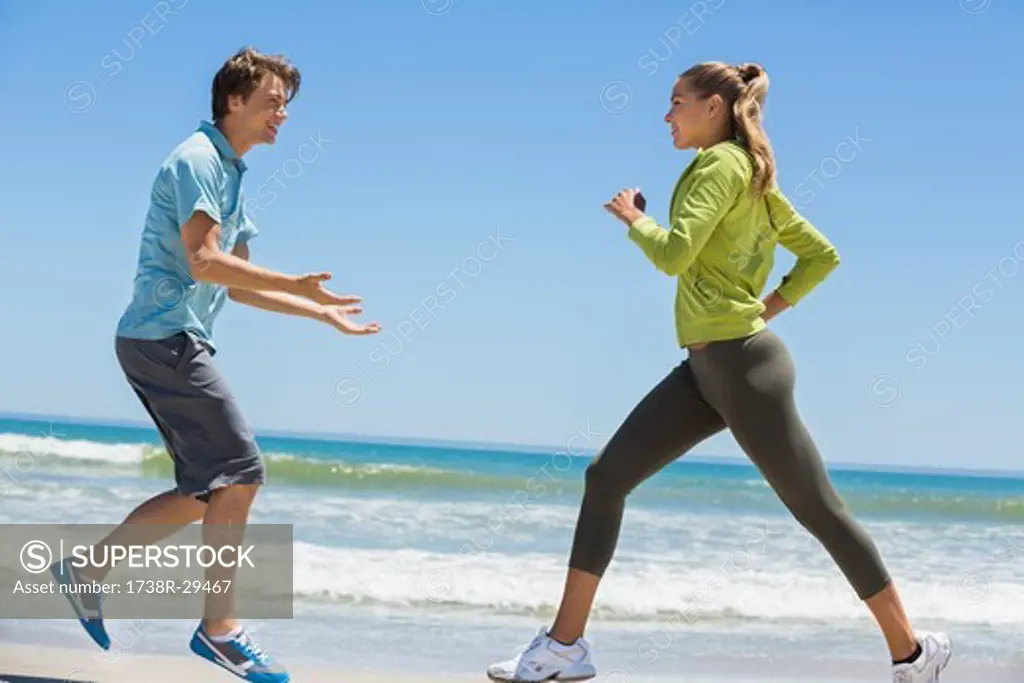 Woman jogging on the beach with her coach