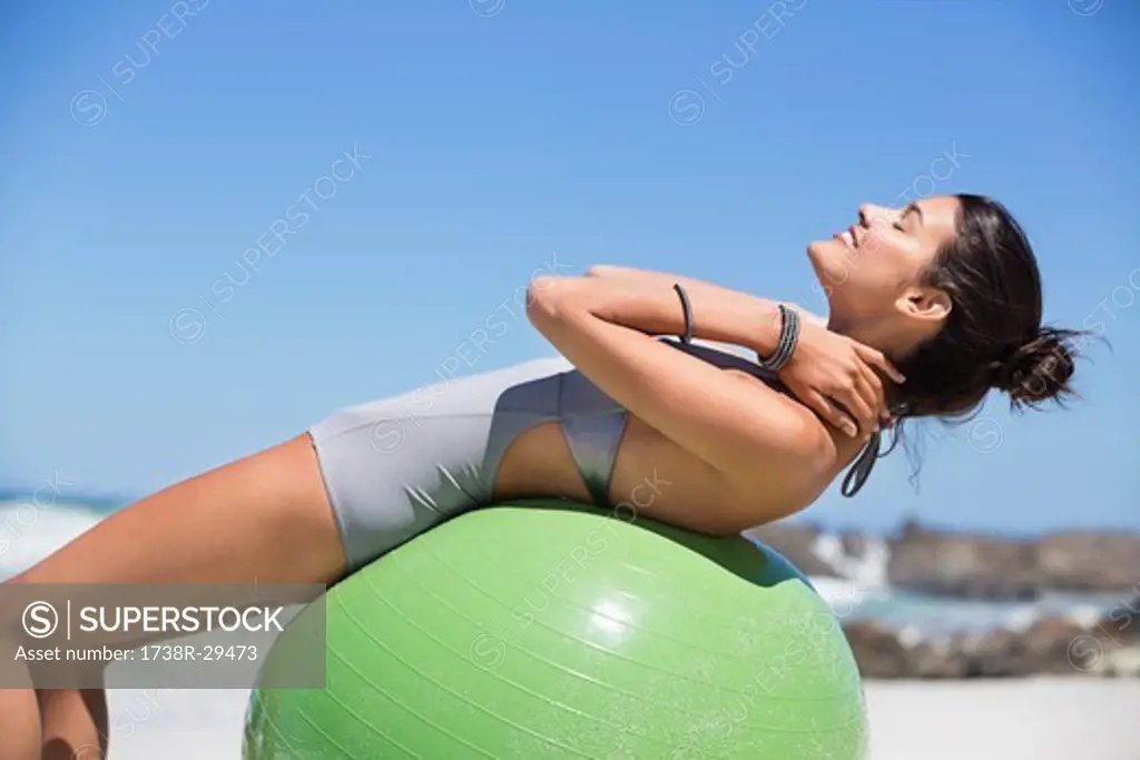 Beautiful woman exercising with fitness ball on the beach