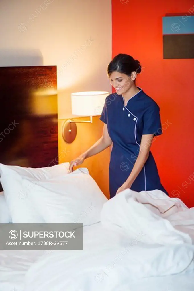 Maid making a bed in a hotel room