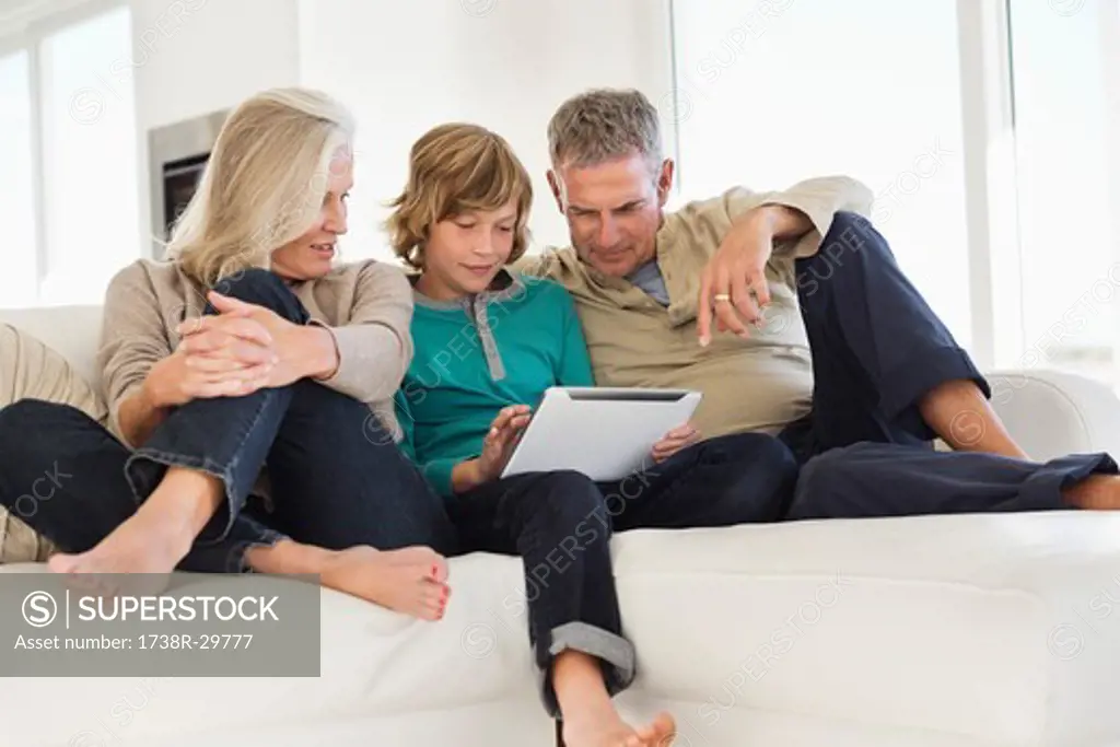 Boy using a digital tablet with his grandparents on a couch
