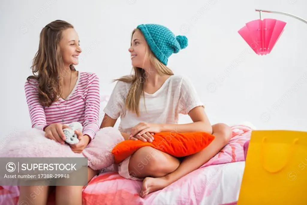 Girls sitting on the bed and talking to each other at a slumber party