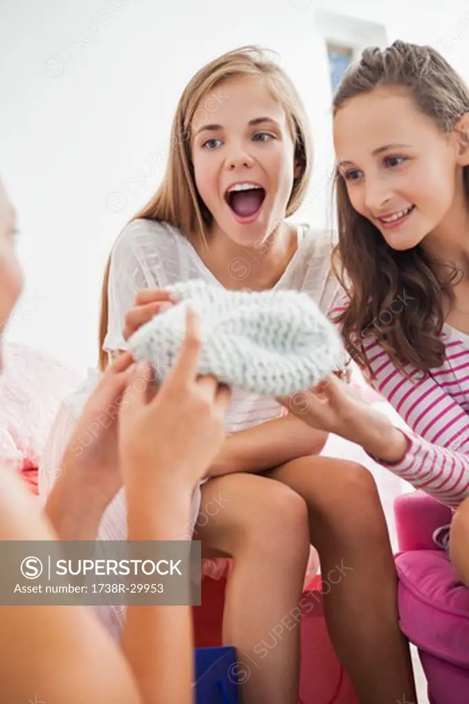 Girl showing knit hat to her friends at a slumber party
