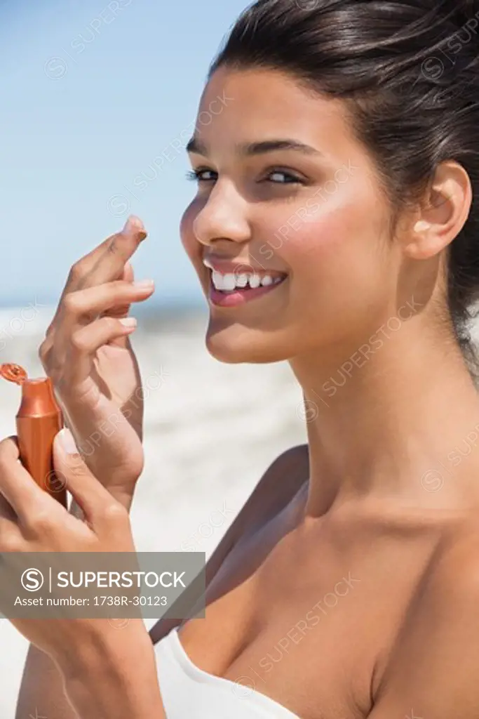 Beautiful woman smelling suntan lotion on the beach