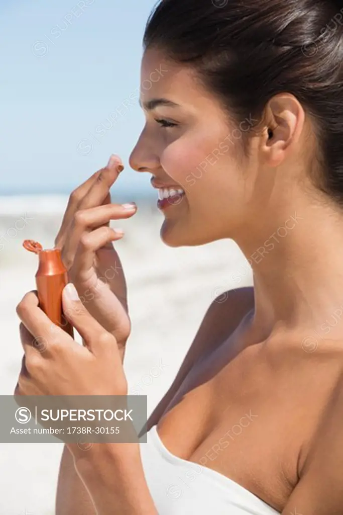 Beautiful woman smelling suntan lotion on the beach