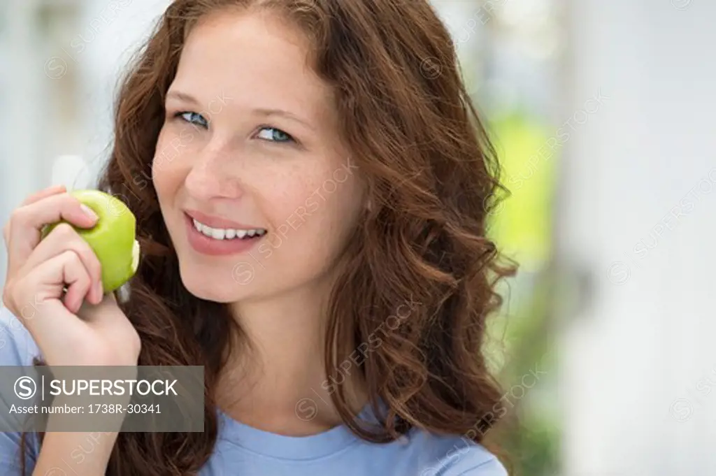 Portrait of a woman eating a green apple