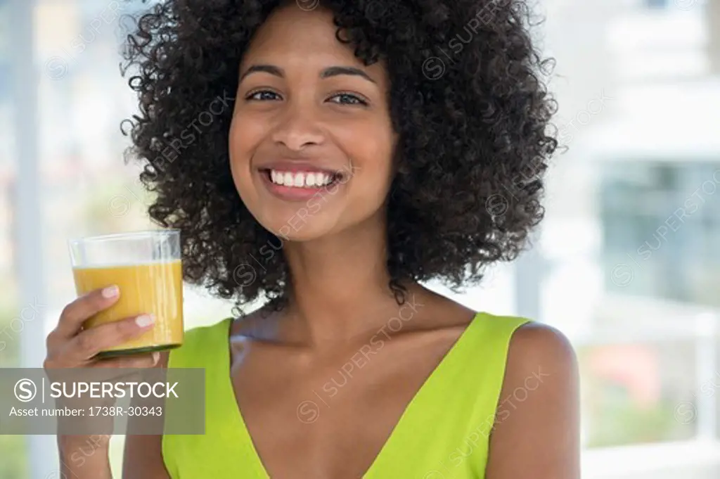 Portrait of a smiling woman holding a glass of mango shake