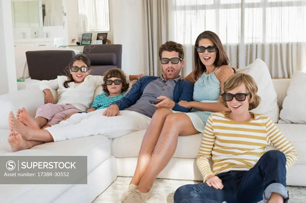 Family watching television at home while wearing 3D glasses