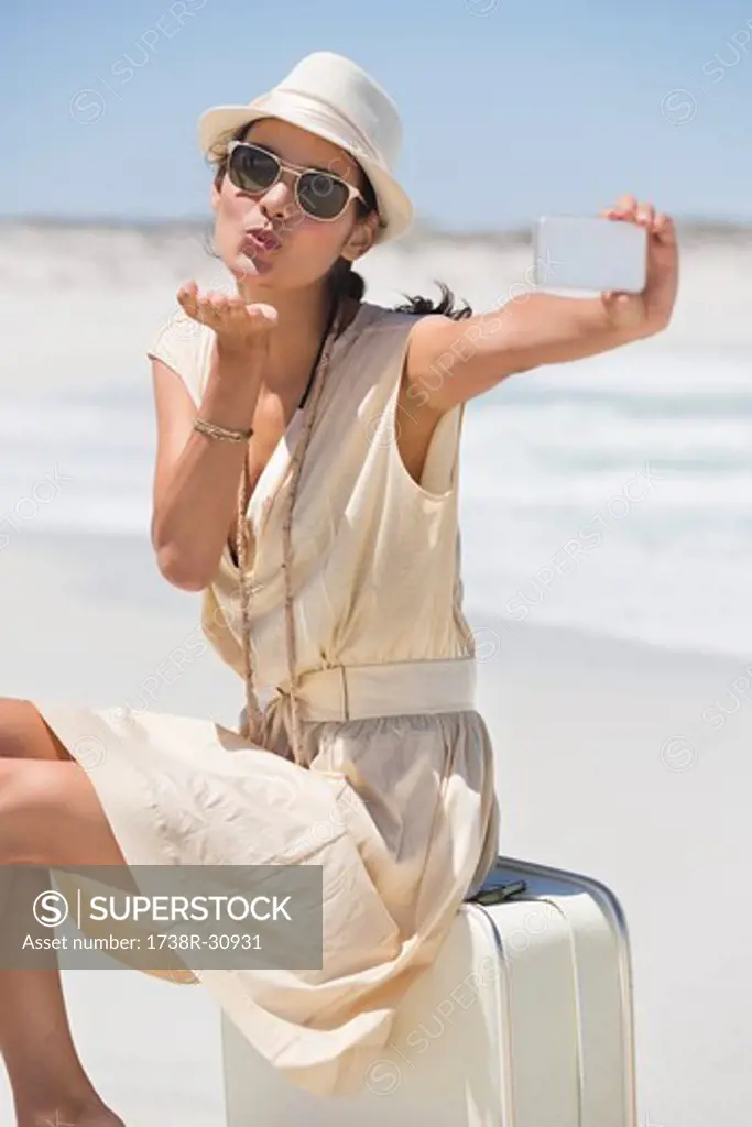 Beautiful woman taking a picture of herself with a cell phone on the beach