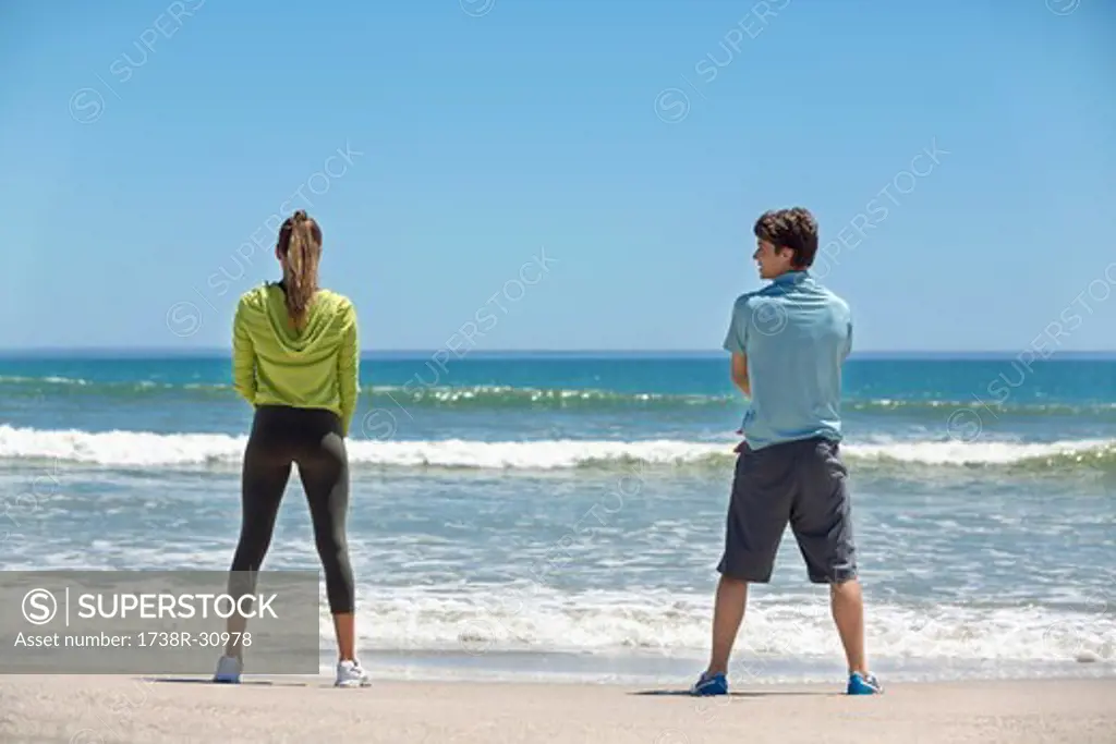 Rear view of a woman and her coach exercising on the beach