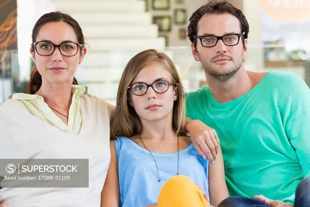 Portrait of a family sitting on a couch and wearing eyeglasses