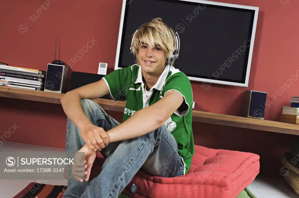 Teenage boy listening to music sitting in living-room