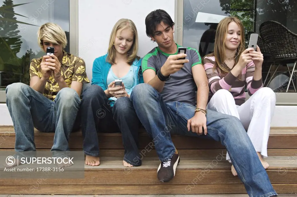 2 teenage boys and 2 teenage girls using their mobile phones