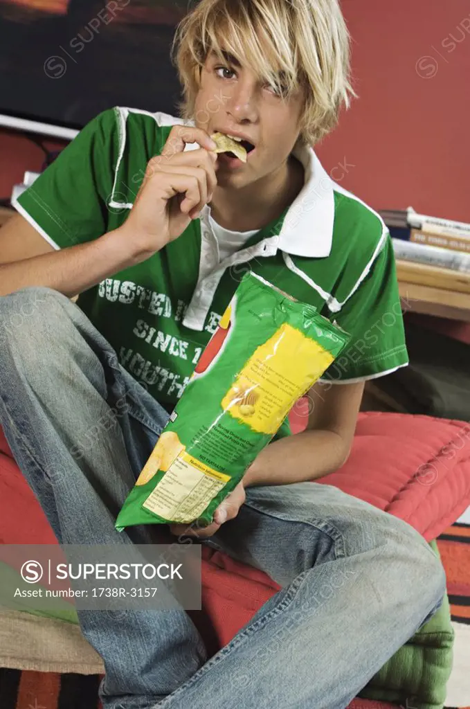 Teenage boy eating crisps