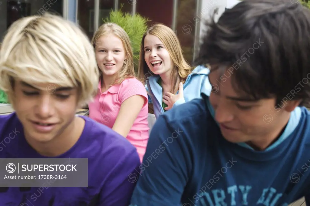 2 teen girls and 2 teen boys smiling, outdoors