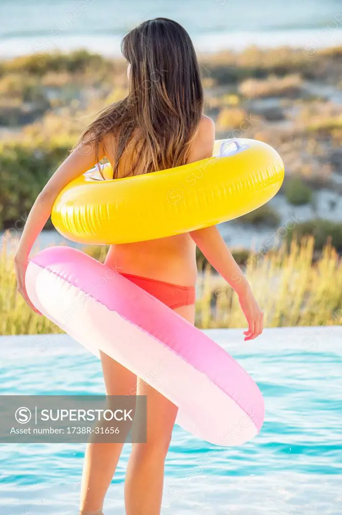 Woman standing with inflatable rings at the poolside