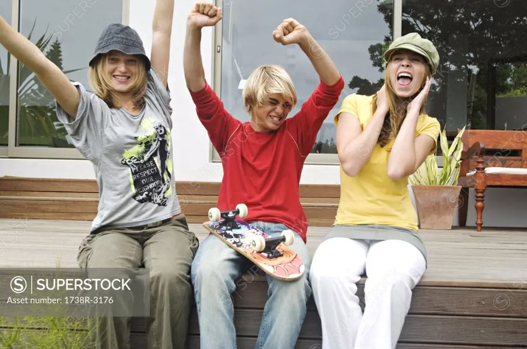 2 teenage girls and boy shouting, sitting on a terrace