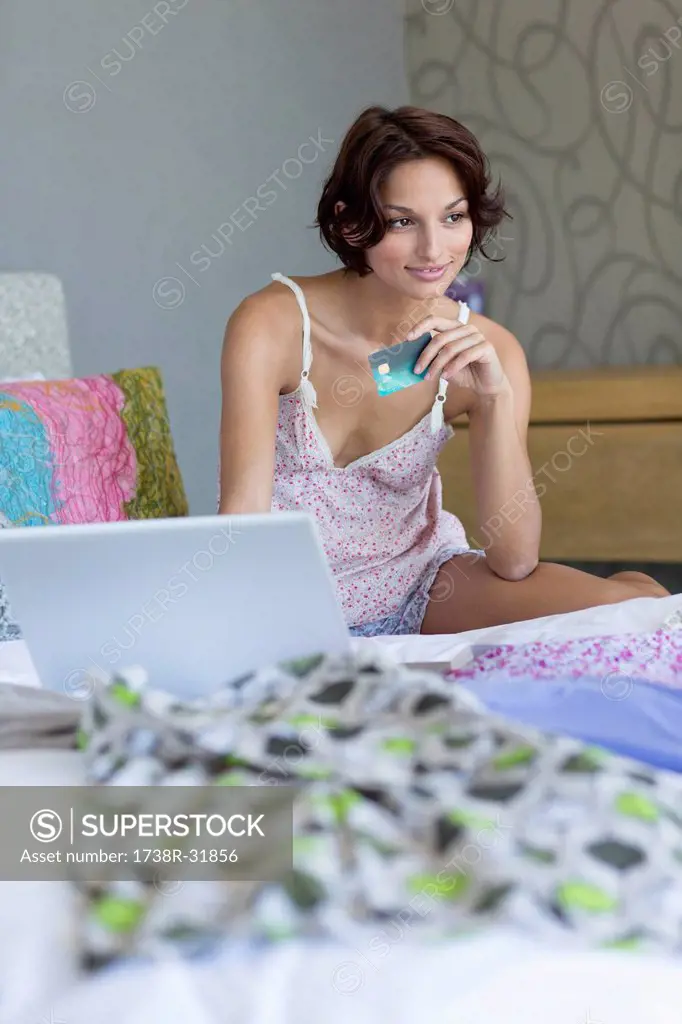 Woman holding credit card and working on a laptop