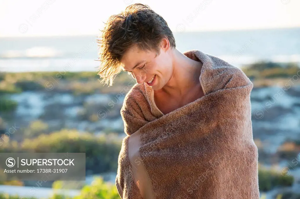 Man wrapped in a towel standing on the beach