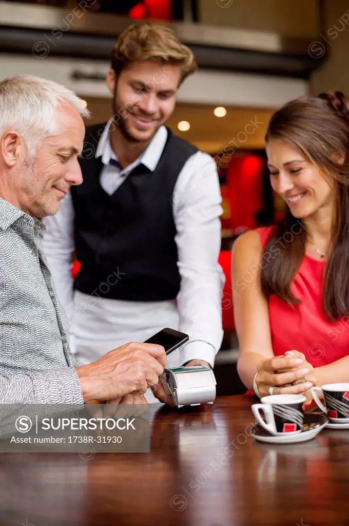 Waiter showing credit card reader to a couple on a table in a restaurant